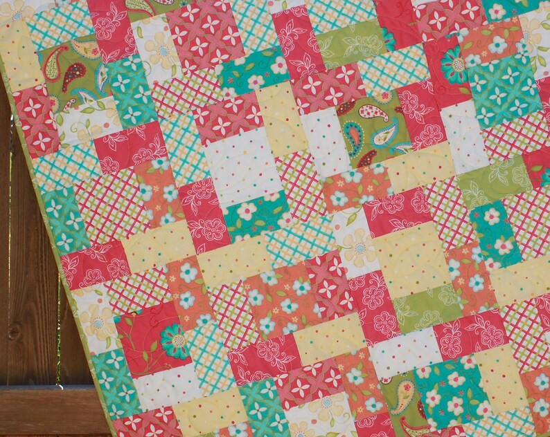 May include: A patchwork quilt with a variety of colorful squares in shades of pink, green, yellow, and blue. The squares feature different patterns, including floral, paisley, and geometric designs.