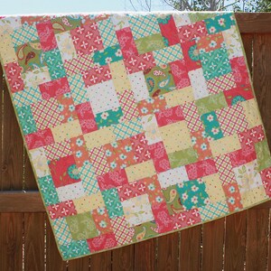 May include: A patchwork quilt with a variety of colorful squares in shades of pink, green, yellow, and blue. The quilt is made of cotton fabric and has a simple, modern design.