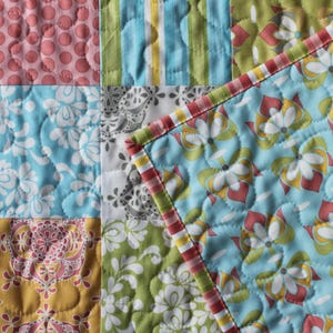 May include: A patchwork quilt with a variety of floral and geometric patterns in shades of blue, green, pink, and yellow.