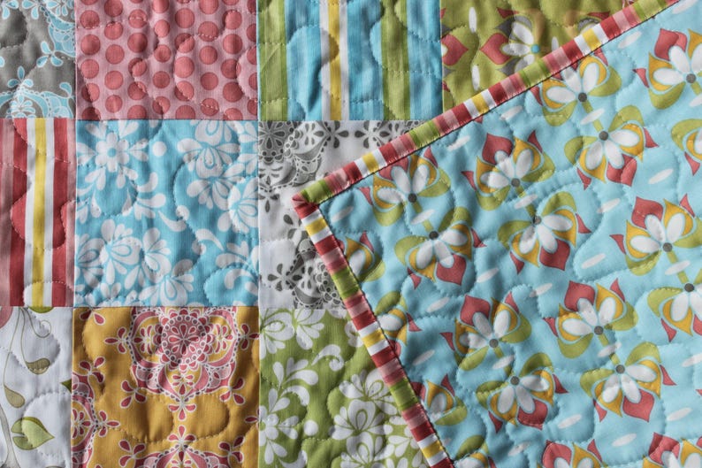 May include: A patchwork quilt with a variety of floral and geometric patterns in shades of blue, green, pink, and yellow.