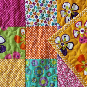 Pu&ograve; includere: Una trapunta colorata a patchwork con una variet&agrave; di motivi floreali e geometrici. La trapunta &egrave; realizzata con colori vivaci come giallo, arancione, rosa, verde e viola.