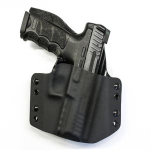 Puede incluir: Una funda de cuero negra con una pistola negra en su interior. La funda tiene varios botones a presi&oacute;n en el lateral.
