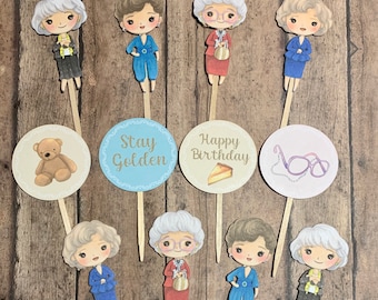 Peut inclure: Ensemble de 10 décorations de cupcakes sur le thème des Golden Girls. Les décorations présentent des illustrations des personnages, dont un ours en peluche, des lunettes et du texte qui dit "Stay Golden" et "Happy Birthday".