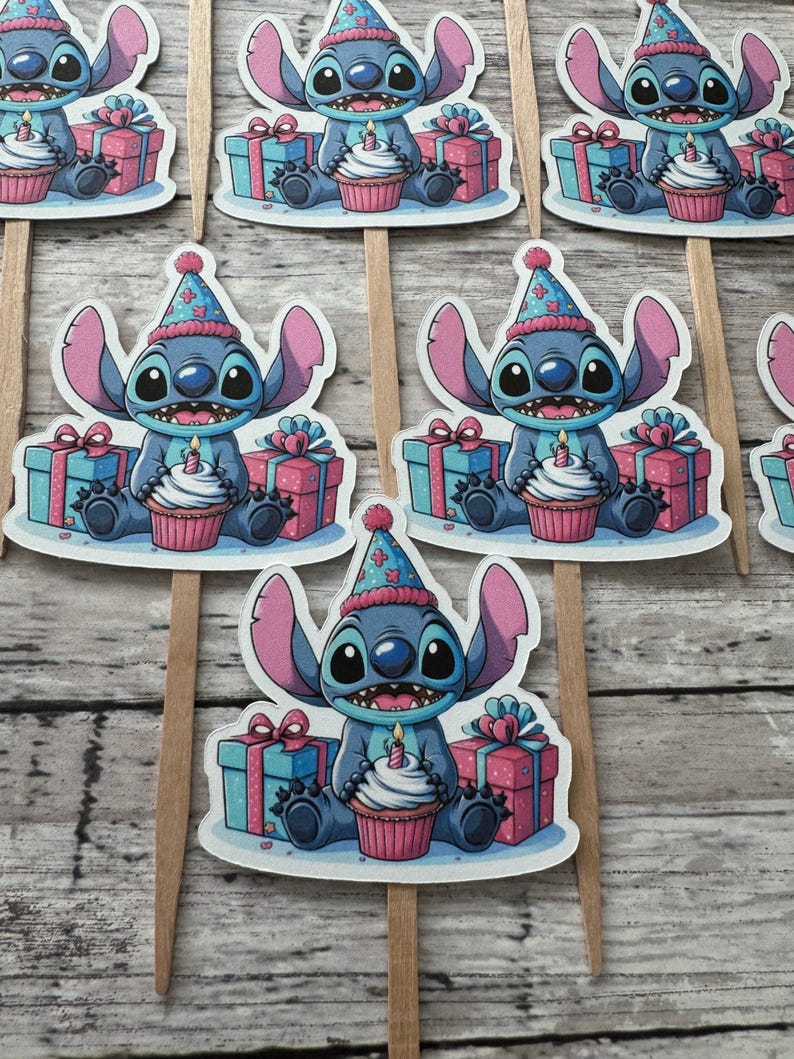 May include: Blue Stitch character wearing a party hat and holding a cupcake with a candle. Stitch is surrounded by presents and sitting on a white background. These are cupcake toppers.