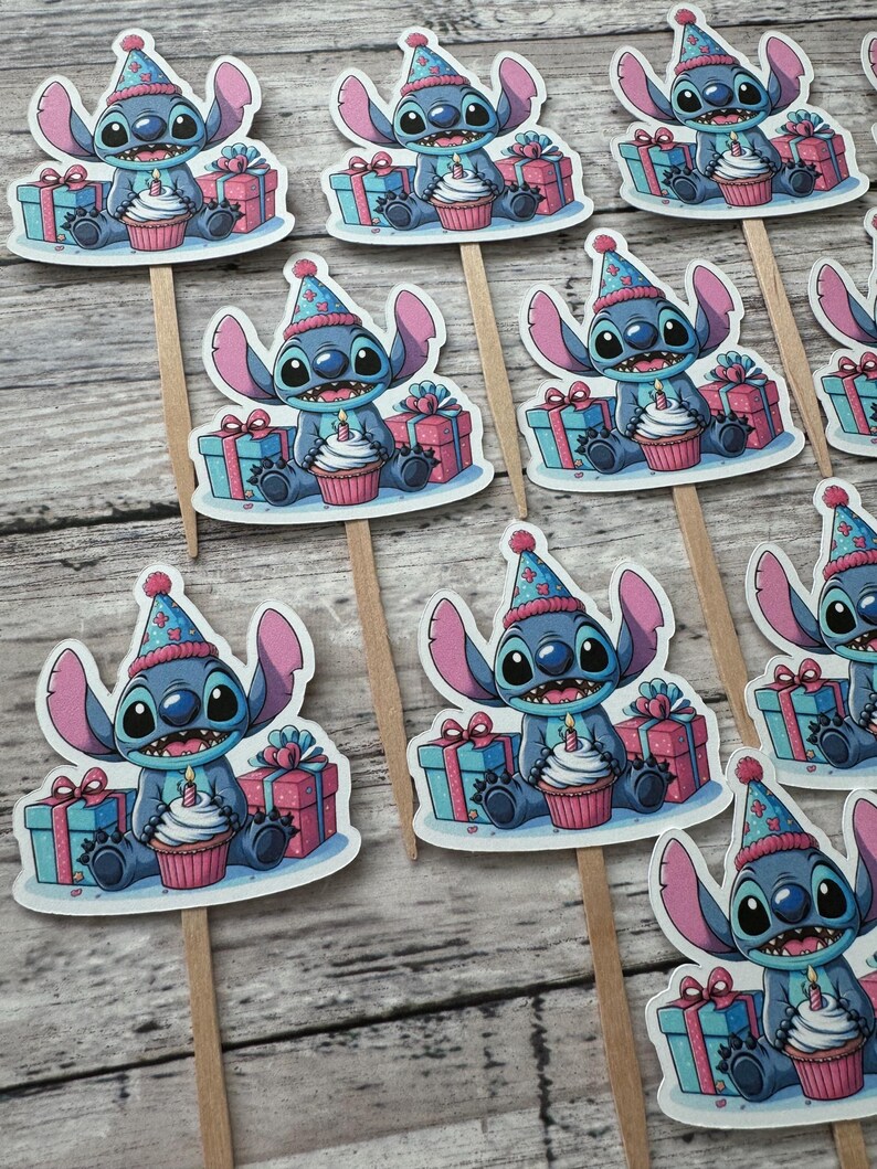 May include: A set of 10 blue Stitch cupcake toppers with a birthday hat, holding a cupcake with a candle and a gift box. The toppers are printed on white cardstock and attached to wooden sticks.