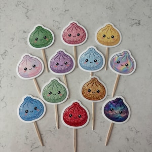 May include: A collection of twelve decorative food picks featuring cute, smiling dumpling illustrations in various colors including green, pink, yellow, purple, blue, and red. Each dumpling has a glittery finish and is attached to a wooden toothpick.