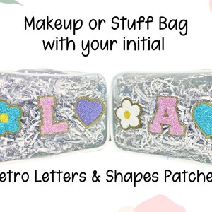 Puede incluir: Dos bolsas rectangulares transparentes rellenas de tiras de papel blanco. La bolsa izquierda tiene una flor azul, una letra L rosa y un corazón morado. La bolsa derecha tiene una flor blanca, una letra A rosa y un corazón azul. Texto: Makeup or Stuff Bag with your initial. Retro Letters & Shapes Patches.