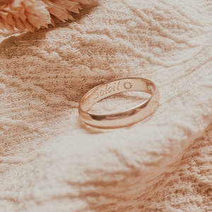 Pu&ograve; includere: Un anello a fascia d'oro con la parola "Soleil" e un simbolo di sole inciso all'esterno.