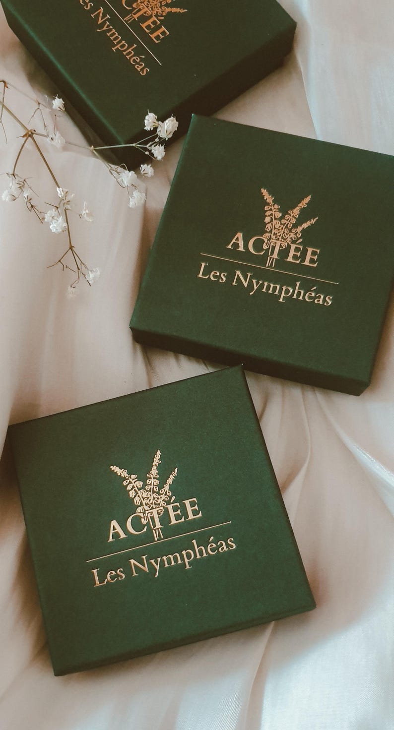 May include: Three green boxes with gold lettering that reads "ACTEE Les Nympheas". The boxes are on a white surface.