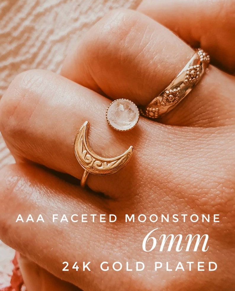 May include: A close-up of three gold-plated rings. One ring is a crescent moon design, another is a band with floral details, and the third is a 6mm faceted moonstone. The text reads "AAA FACETED MOONSTONE" and "24K GOLD PLATED".