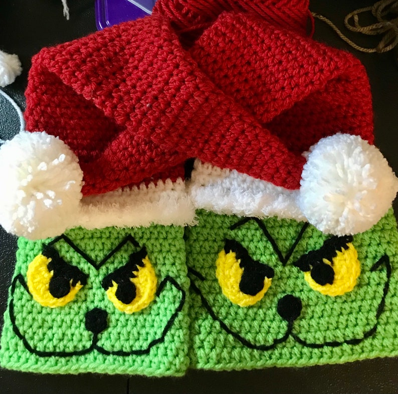 May include: A pair of green crocheted Grinch-themed boot cuffs with white fur trim and red crocheted Santa hats with white pom-poms.
