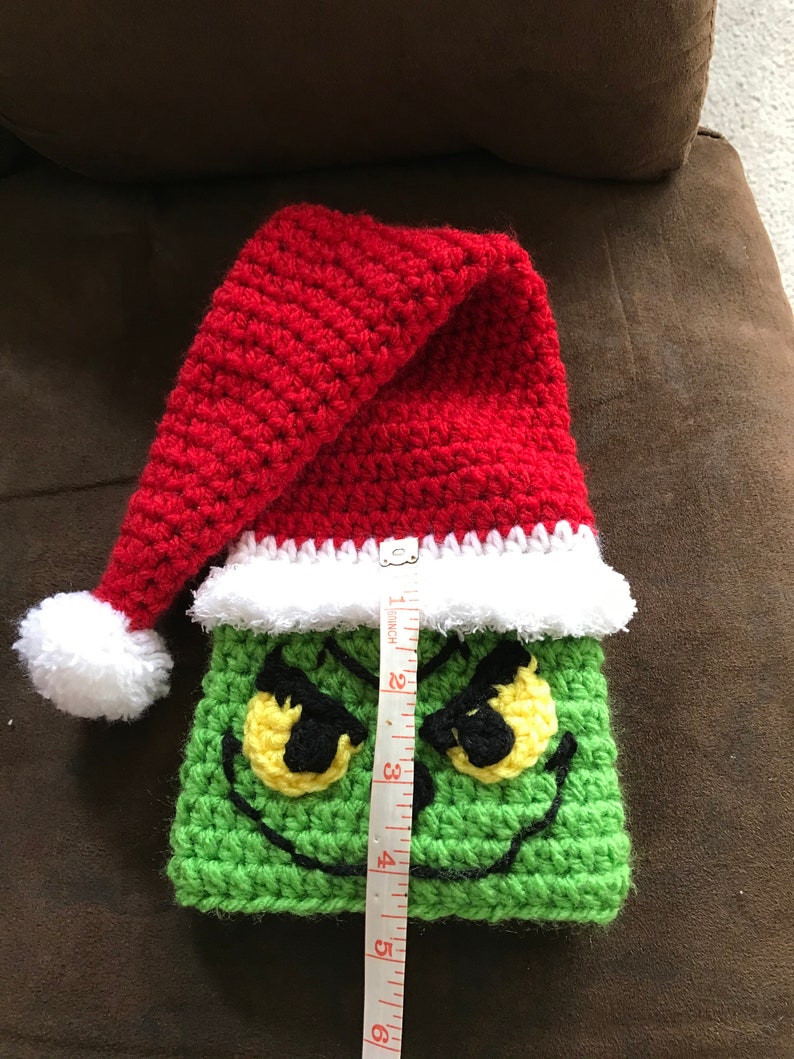 May include: Green crocheted Grinch stocking with a red crocheted Santa hat and white pom-pom. The stocking is 6 inches tall.