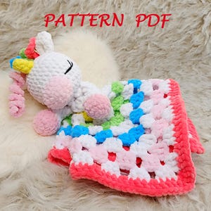 May include: A crochet unicorn lovey featuring a white head with a pink snout, closed eyes, and a colorful mane of pink, yellow, blue, and green yarn. Attached is a square granny square blanket in white, blue, green, and pink with a bright pink border. Text reads PATTERN PDF.