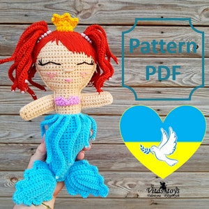 May include: Crochet pattern PDF for a mermaid doll with red hair, a blue tail, and a pink top. The pattern includes a heart with the Ukrainian flag and a dove holding an olive branch.  The text "Pattern PDF" is in a decorative frame.