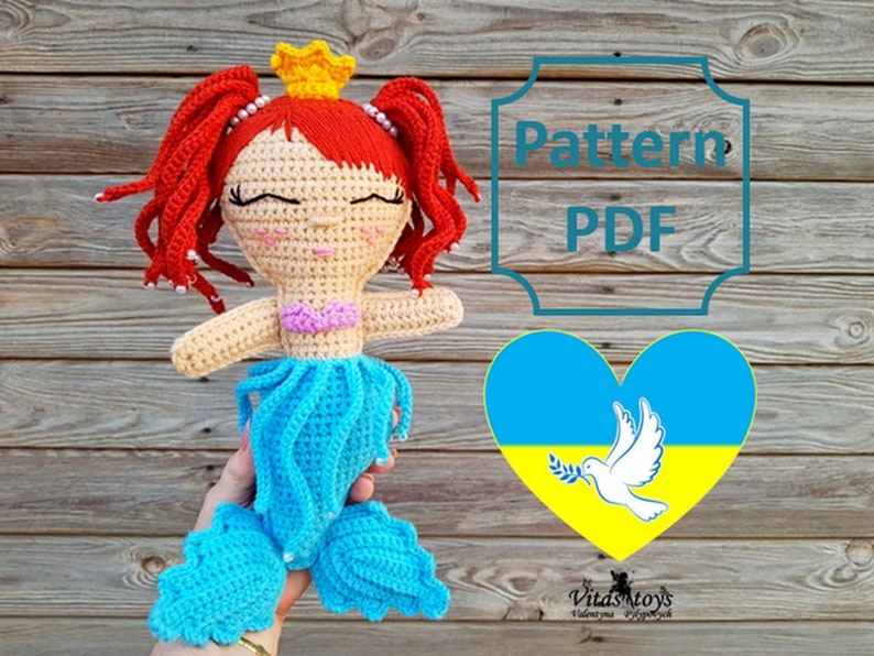 May include: Crochet pattern PDF for a mermaid doll with red hair, a blue tail, and a pink top. The pattern includes a heart with the Ukrainian flag and a dove holding an olive branch.  The text "Pattern PDF" is in a decorative frame.