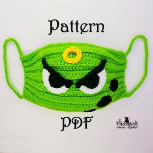 May include: A green crocheted face mask with a monster face design. The mask features white and black eyes, a yellow circular detail, and black spots. The word "Pattern" is above the mask, and "PDF" is below.