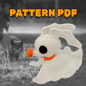 Op de afbeelding: Een gehaakt wit spookachtig karakter met een zwart oog, een oranje neus en kraag. De tekst "PATTERN PDF" staat bovenaan. Een grijze kat staat op de achtergrond.