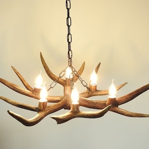 Authentic deer antlers form the structure of this stunning chandelier, boasting 6 arms with bulbs. Antler fragments cleverly camouflage bulb holders. Height is easily adjustable thanks to the chain suspension.