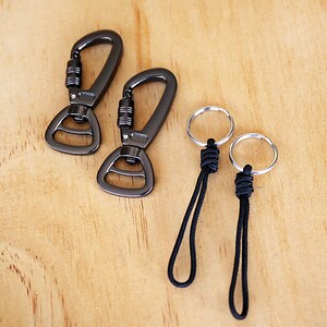 May include: Two black metal clips and two black cord keychains with silver rings.