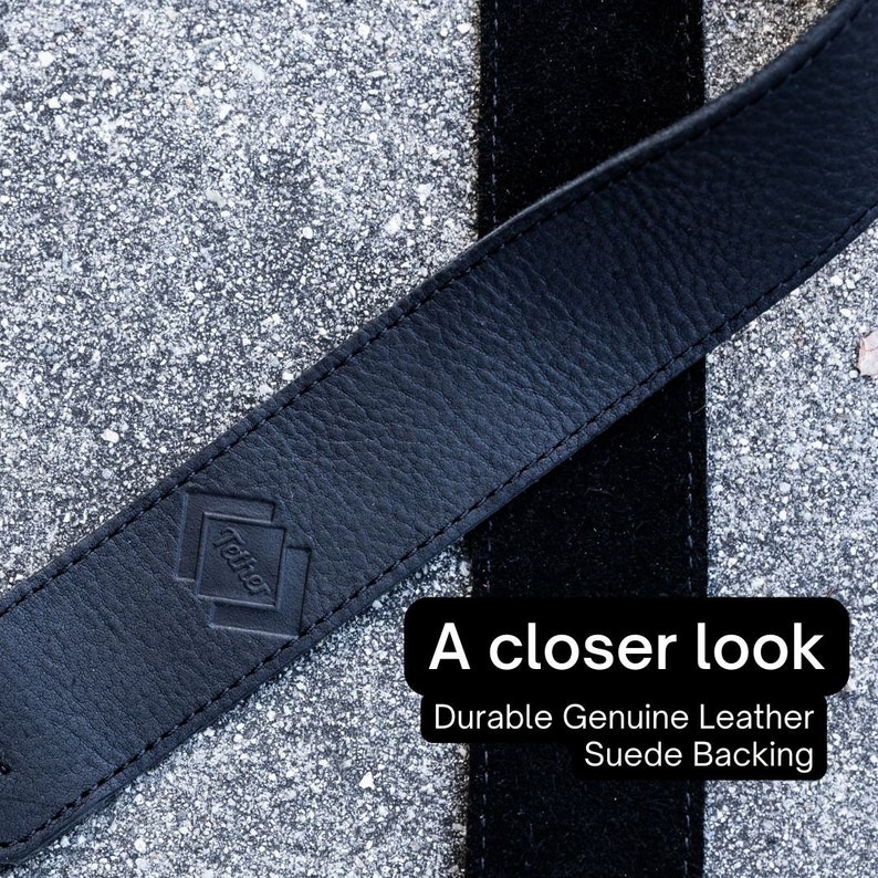 May include: Close-up of a black leather strap with a suede backing. The strap has a diamond-shaped logo with the word "Tether" embossed on it.