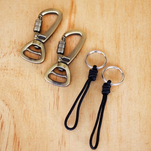 May include: Two gold-toned metal clips with a black cord attached to two silver rings. The cord is knotted at the top of each ring.