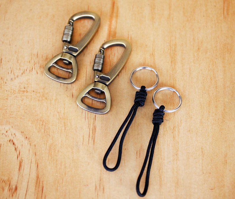 May include: Two gold-toned metal clips with a black cord attached to two silver rings. The cord is knotted at the top of each ring.