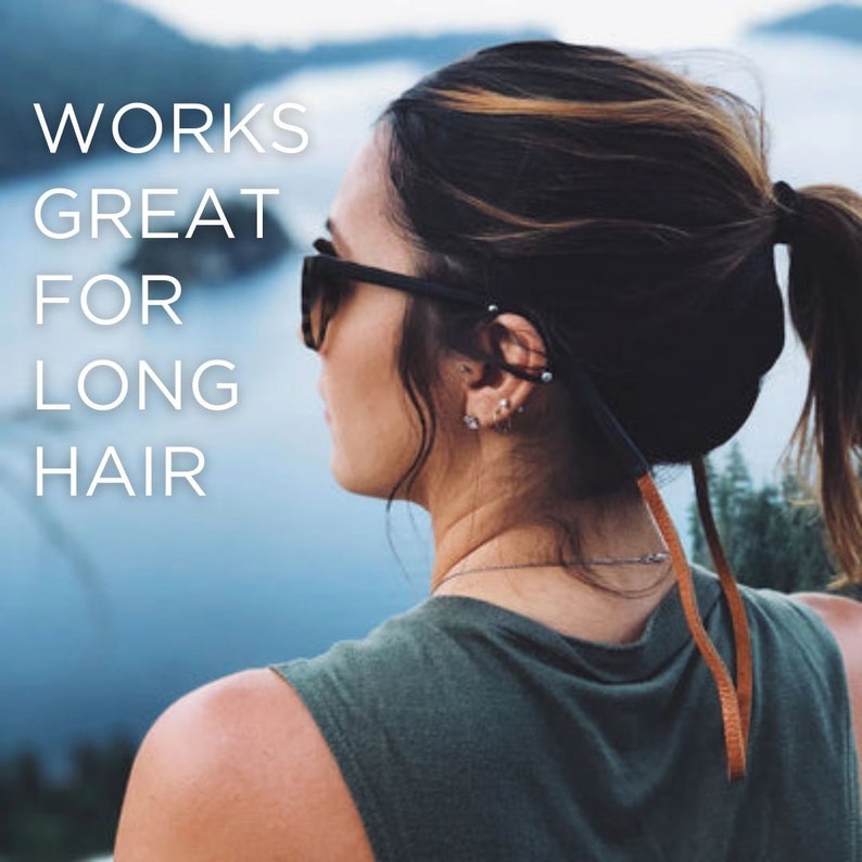 Peut inclure: Une femme avec de longs cheveux bruns portant un d&eacute;bardeur vert et des lunettes de soleil avec une sangle brune attach&eacute;e aux lunettes. La sangle est pass&eacute;e autour de sa queue de cheval. Le texte "WORKS GREAT FOR LONG HAIR" est visible sur l'image.
