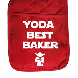 May include: A red oven mitt with the text "YODA BEST BAKER" in white, along with a white graphic of Yoda. The mitt has a quilted pattern and a pocket.