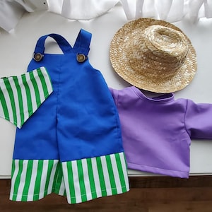 May include: A set of doll clothing including blue overalls with green and white striped cuffs, a matching green and white striped triangular bandana, a solid purple long-sleeve shirt, and a woven straw hat with a wide brim and a rounded crown.