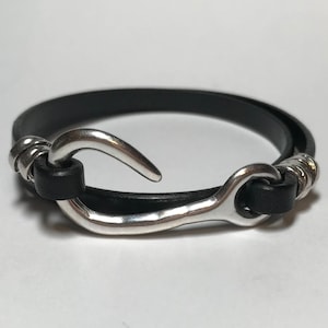 May include: A black leather bracelet with a silver hook clasp.