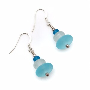 May include: A pair of silver dangle earrings with three blue and white glass beads. The beads are stacked on top of each other, with the largest bead at the bottom.