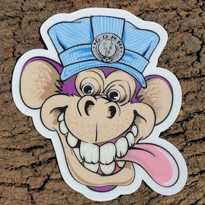 May include: A purple monkey wearing a blue and white striped engineer's cap with a silver lightning bolt logo. The monkey has a wide grin and its tongue is sticking out.