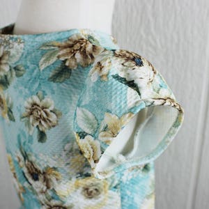 May include: A light blue dress with a floral print. The dress has short sleeves and a round neckline.