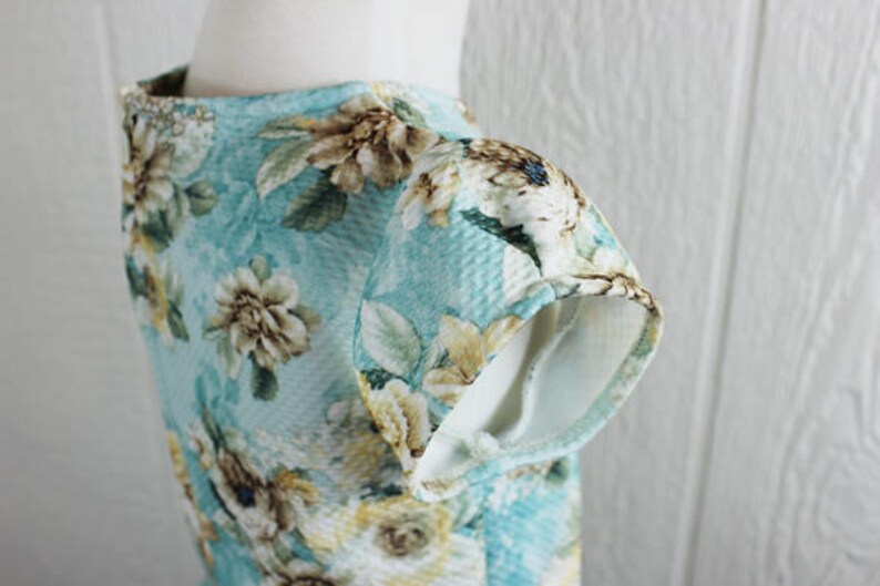 May include: A light blue dress with a floral print. The dress has short sleeves and a round neckline.