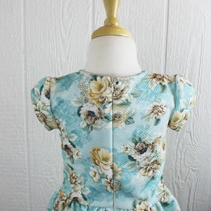 May include: A light blue dress with a floral print. The dress has short sleeves and a gathered skirt.