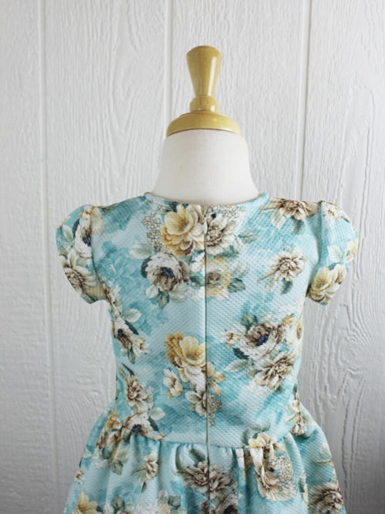 May include: A light blue dress with a floral print. The dress has short sleeves and a gathered skirt.