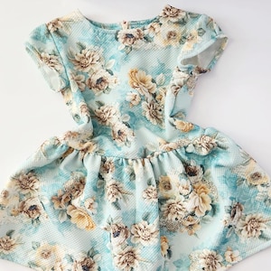 May include: A light blue dress with a floral print. The dress has short sleeves and a ruffled skirt.