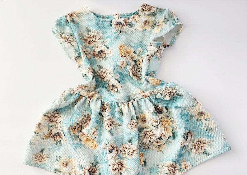 May include: A light blue dress with a floral print. The dress has short sleeves and a ruffled skirt.