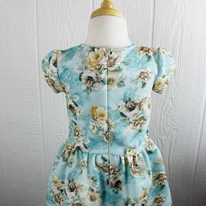 May include: A light blue dress with a floral print. The dress has a ruffled hem and short sleeves.
