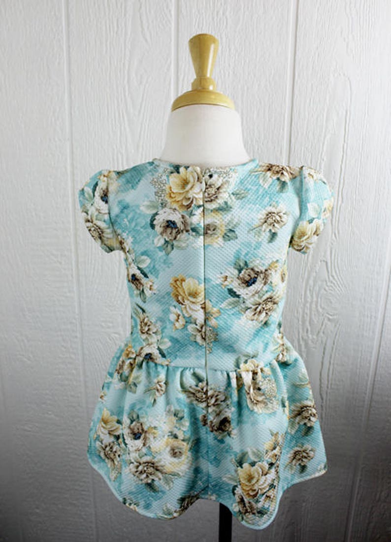 May include: A light blue dress with a floral print. The dress has a ruffled hem and short sleeves.