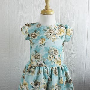 May include: A light blue dress with a floral print. The dress has short sleeves and a ruffled hem.