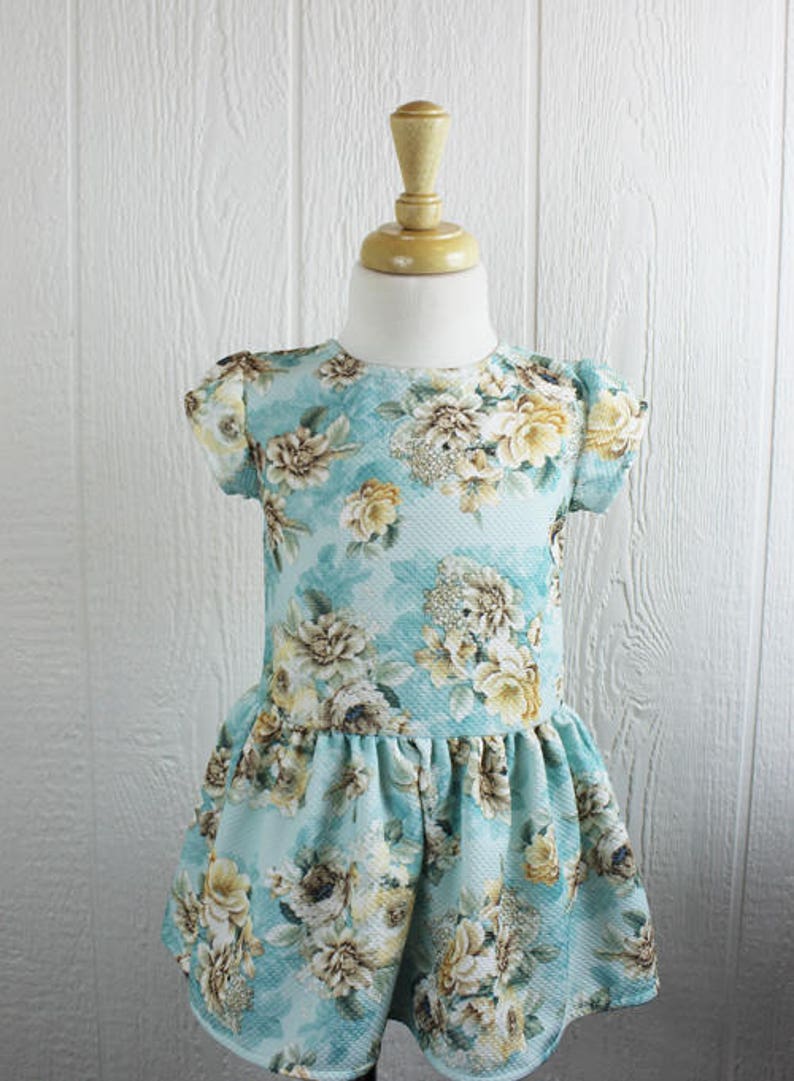 May include: A light blue dress with a floral print. The dress has short sleeves and a ruffled hem.