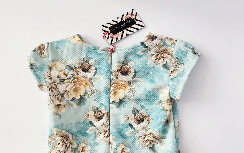 May include: A light blue dress with a floral print. The dress has short sleeves and a round neckline. The dress is made of a soft, comfortable fabric.