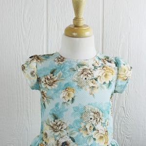 May include: A light blue dress with a floral print. The dress has short sleeves and a ruffled hem.