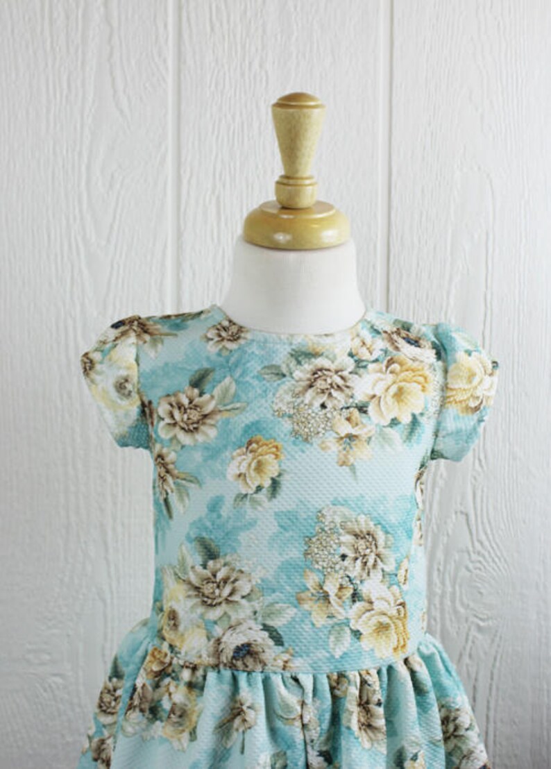 May include: A light blue dress with a floral print. The dress has short sleeves and a ruffled hem.