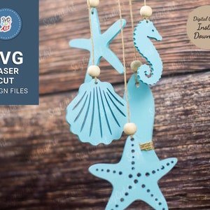 May include: A set of five blue wooden sea-themed ornaments, including a starfish, a seashell, a seahorse, and two fish, hanging from a wooden surface.