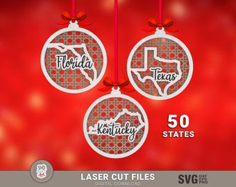 Pode incluir: Três recortes de enfeites de Natal brancos com um design estampado. Cada enfeite apresenta um contorno de estado e o nome do estado: Flórida, Texas e Kentucky. Os enfeites estão sobre um fundo vermelho com o texto "50 ESTADOS".