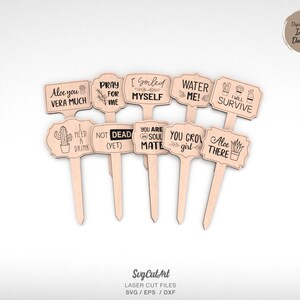 May include: Set of ten wooden plant markers with humorous sayings about plants and cacti. The markers are laser cut and feature a variety of designs, including cacti, succulents, and aloe vera plants. The sayings include "Aloe you vera much", "Pray for me", "I gorled myself", "Water me!", "I will survive", "I need a drink", "Not dead (yet)", "You are my soul mate", "You grow girl", and "Aloe there".