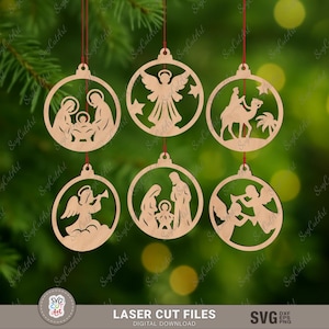 Könnte beinhalten: Sechs hölzerne Weihnachtskugeln mit roten Aufhängeschnüren. Jede Kugel zeigt ein lasergeschnittenes Design religiöser Figuren, darunter Engel, die Krippe und die Heiligen Drei Könige. Die Kugeln hängen vor einem grünen Hintergrund.