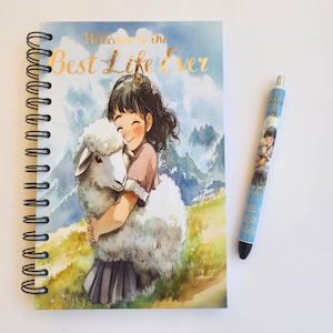 May include: A spiral bound notebook with a watercolor illustration of a girl hugging a sheep. The notebook cover has the text "Welcome to the Best Life Ever" in gold lettering.